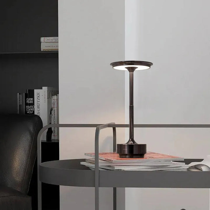 "Elegant wireless table lamp with sleek curves, gold finish; perfect for versatile ambient lighting on any table or desk."