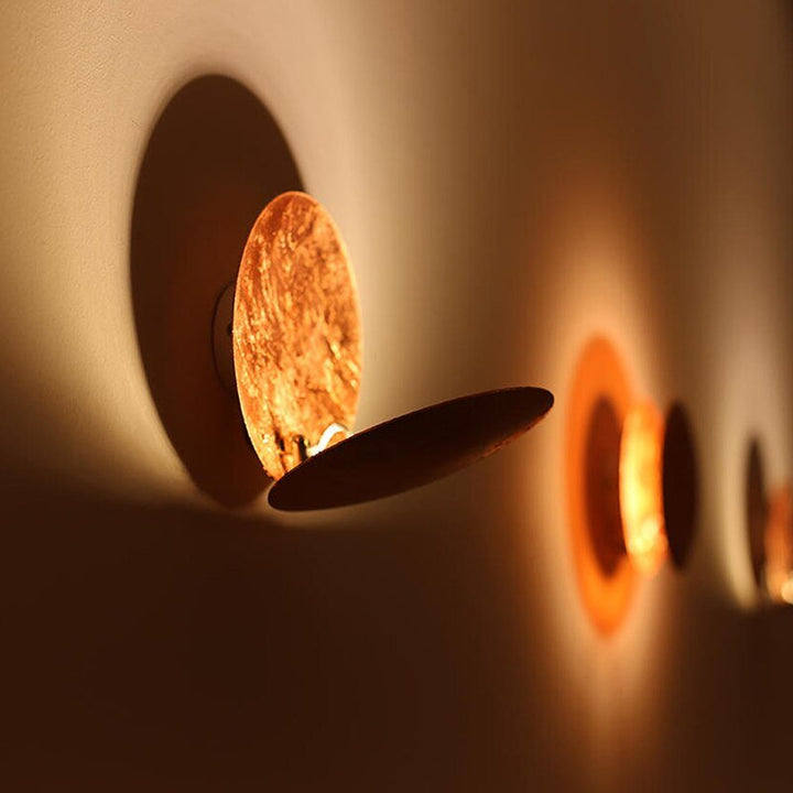 "Golden Solaris Wall Lamp with eclipse-inspired design, featuring elegant gold discs and warm LED glow for home decor."