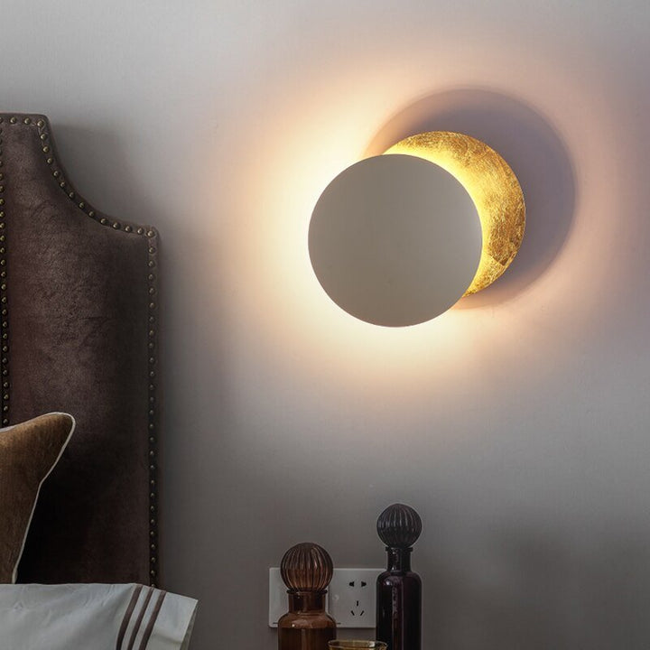 "Golden Solaris Wall Lamp with eclipse-inspired design, featuring elegant gold discs and warm LED glow for home decor."