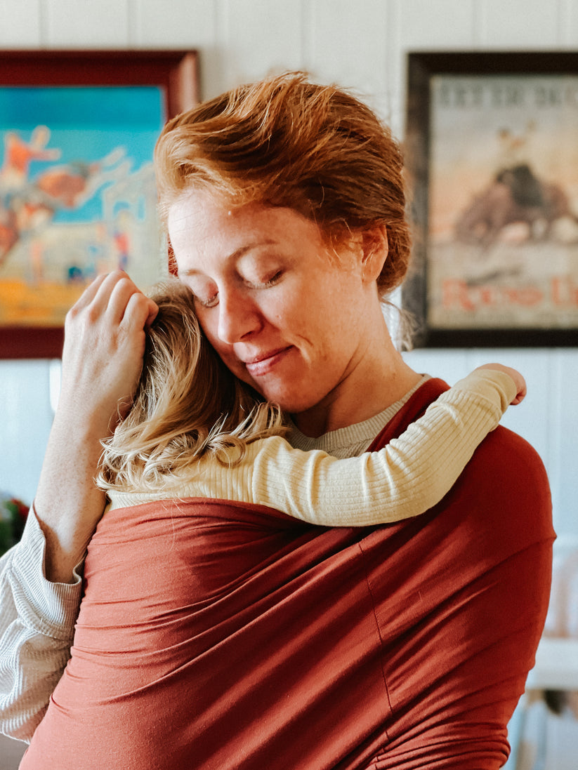 "Unisex ergonomic baby wrap carrier, grey, enveloping baby and parent comfortably for hands-free convenience."