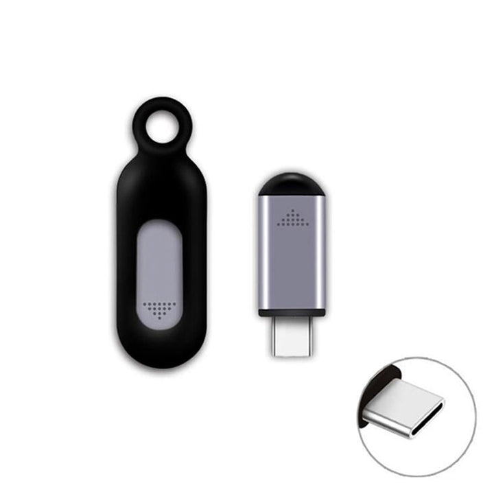Portable black infrared remote control for smartphones, placed on a desk alongside a laptop