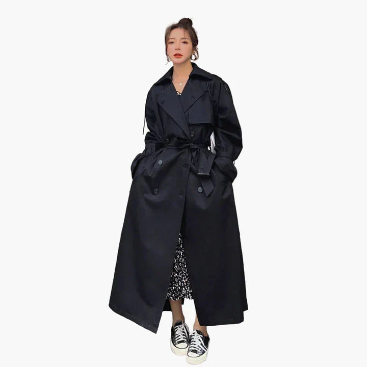 Close-up of the fabric texture and double-breasted buttons on a women's chic long loose-fit trench coat.
