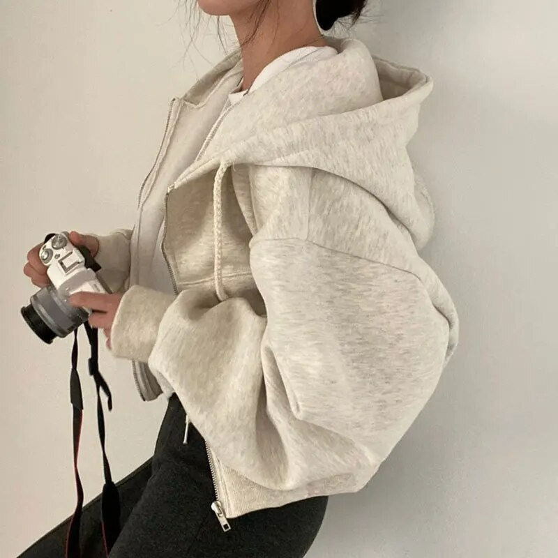 Woman wearing a fashionable cropped zip-up winter hoodie, suitable for everyday casual wear.