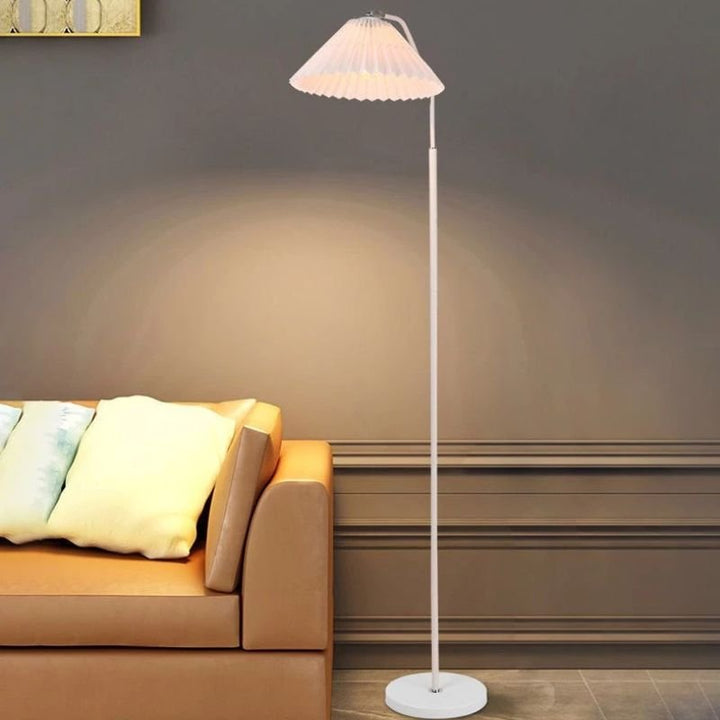 Elegant floor lamp with pleated fabric shade, soft warm lighting, crafted from metal, perfect for living rooms or bedrooms.