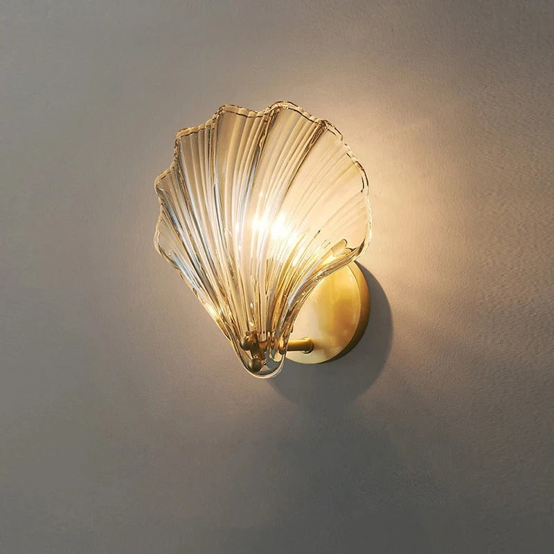 "Elegant shell-shaped glass wall sconce, inspired by coastal design, provides warm ambient lighting for home décor."