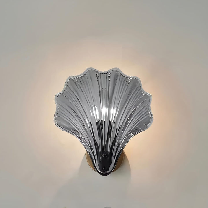 "Elegant shell-shaped glass wall sconce, inspired by coastal design, provides warm ambient lighting for home décor."