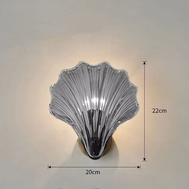 "Elegant shell-shaped glass wall sconce, inspired by coastal design, provides warm ambient lighting for home décor."