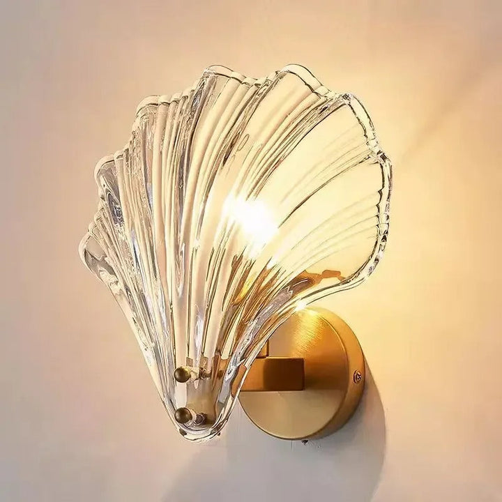 "Elegant shell-shaped glass wall sconce, inspired by coastal design, provides warm ambient lighting for home décor."