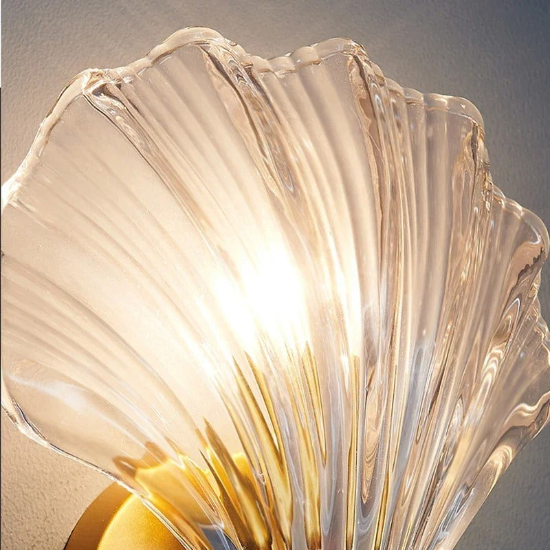 "Elegant shell-shaped glass wall sconce, inspired by coastal design, provides warm ambient lighting for home décor."