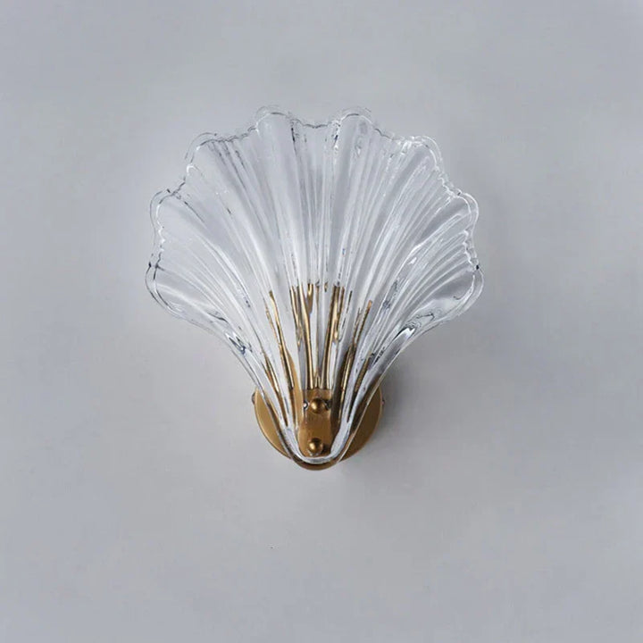 "Elegant shell-shaped glass wall sconce, inspired by coastal design, provides warm ambient lighting for home décor."