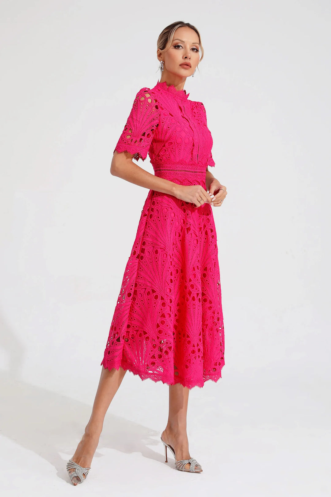 Side profile of a woman showcasing the flowing silhouette of a pink lace midi dress.