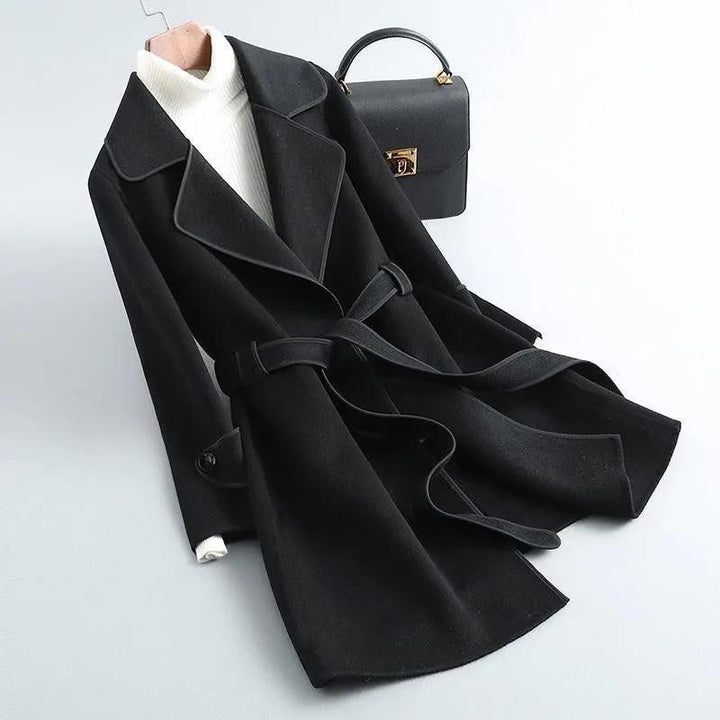 Close-up of the textured wool-blend fabric and contrast piping on a women's belted longline coat