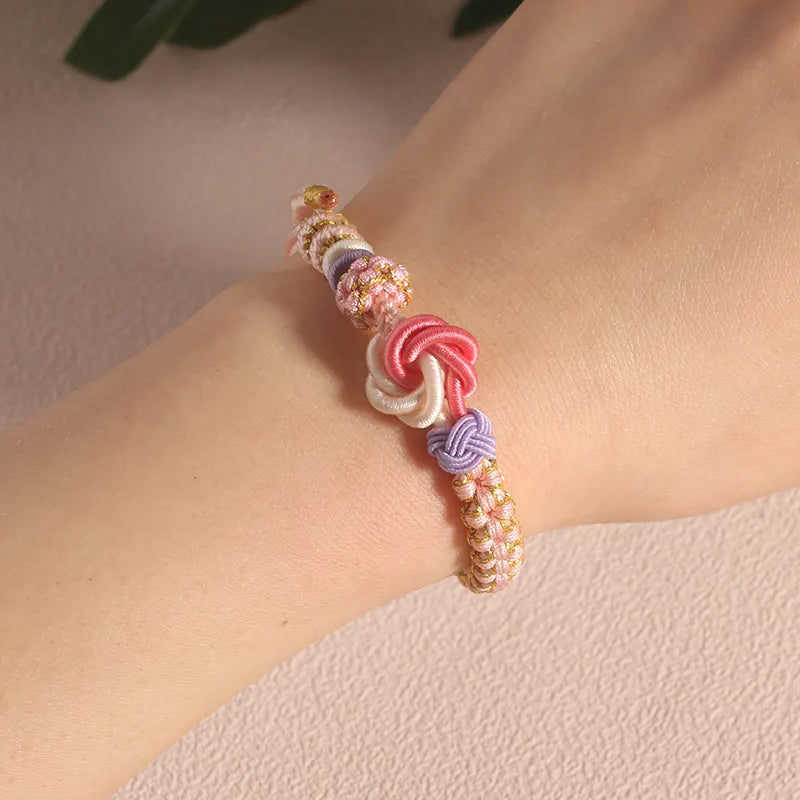 Stack of multiple peach blossom knot braided bracelets for girls, showcasing vibrant peach & pink colors