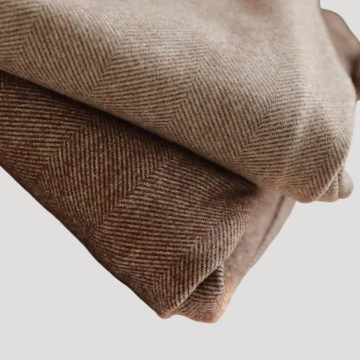 Men's tailored ankle-length pants in brown, folded neatly to display the cut and fit of the garment.