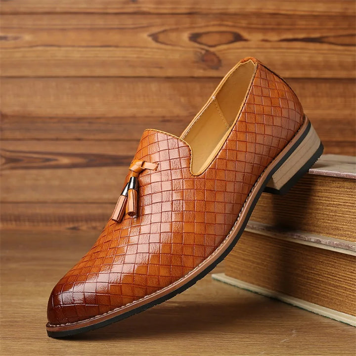 Men's fashion footwear: textured black tassel loafers on a light background, versatile style