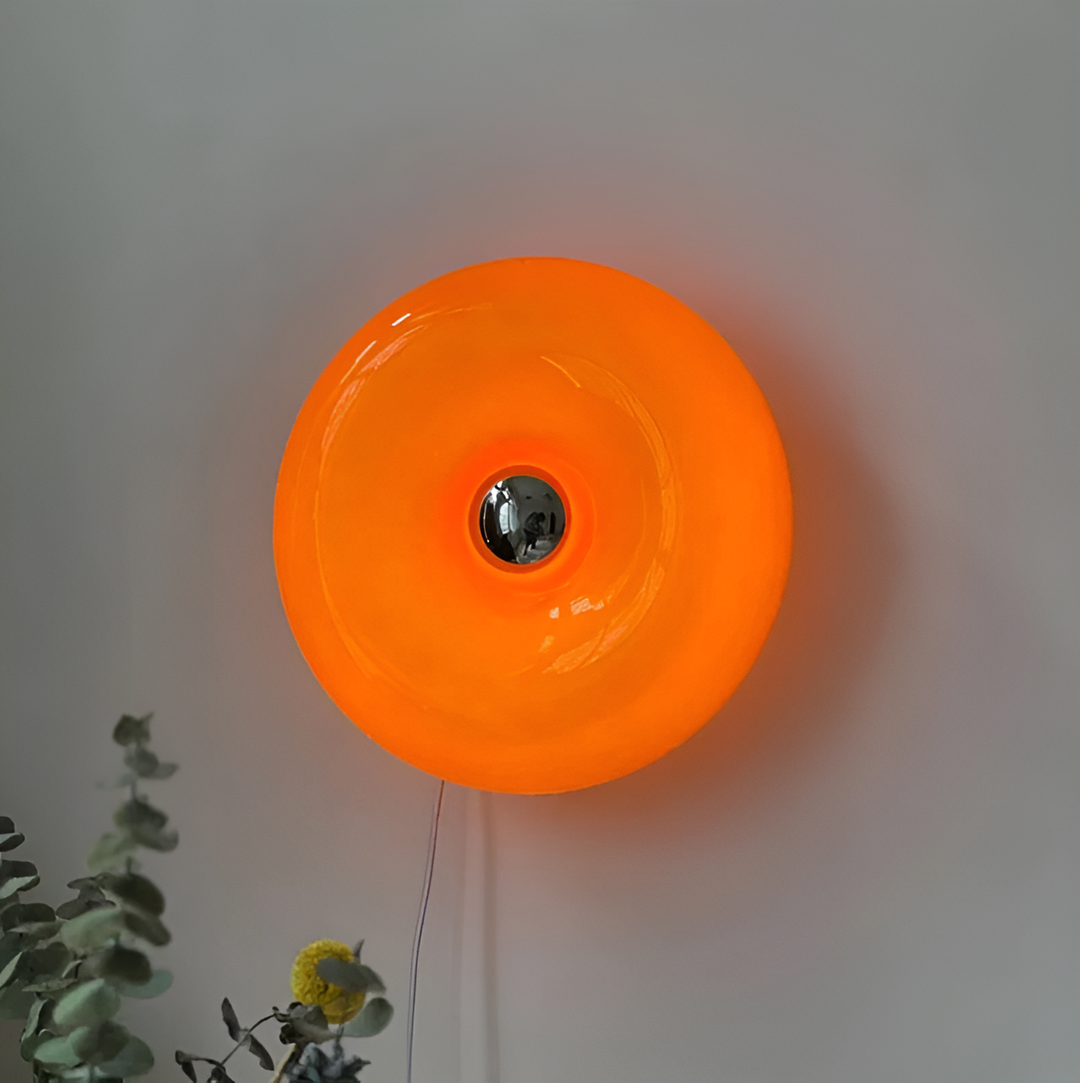 Orange donut-shaped LED lamp with warm glow, fits as a wall or table lamp, whimsical design with high-quality glass and metal