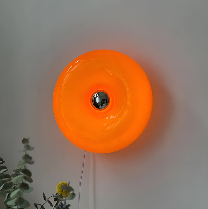 Orange donut-shaped LED lamp with warm glow, fits as a wall or table lamp, whimsical design with high-quality glass and metal