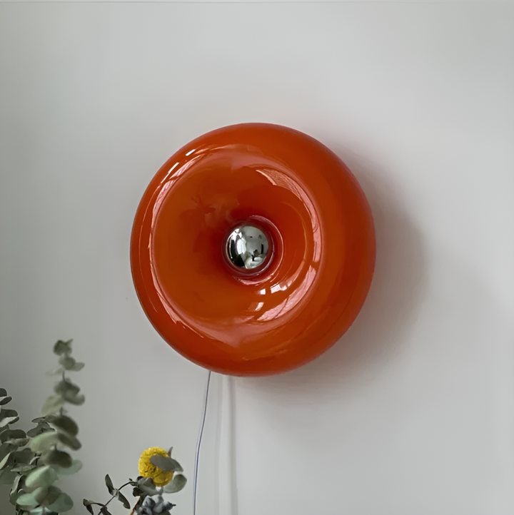 Orange donut-shaped LED lamp with warm glow, fits as a wall or table lamp, whimsical design with high-quality glass and metal