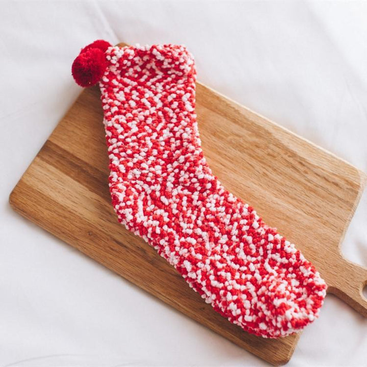 Woman's hands holding a pair of new fluffy cupcake slipper socks, ready for gifting.