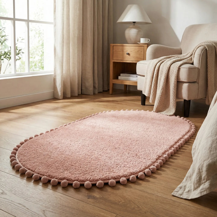 Chic oval pompom bath rug with plush texture. An absorbent and non-slip bathroom mat, enhancing modern home decor.
