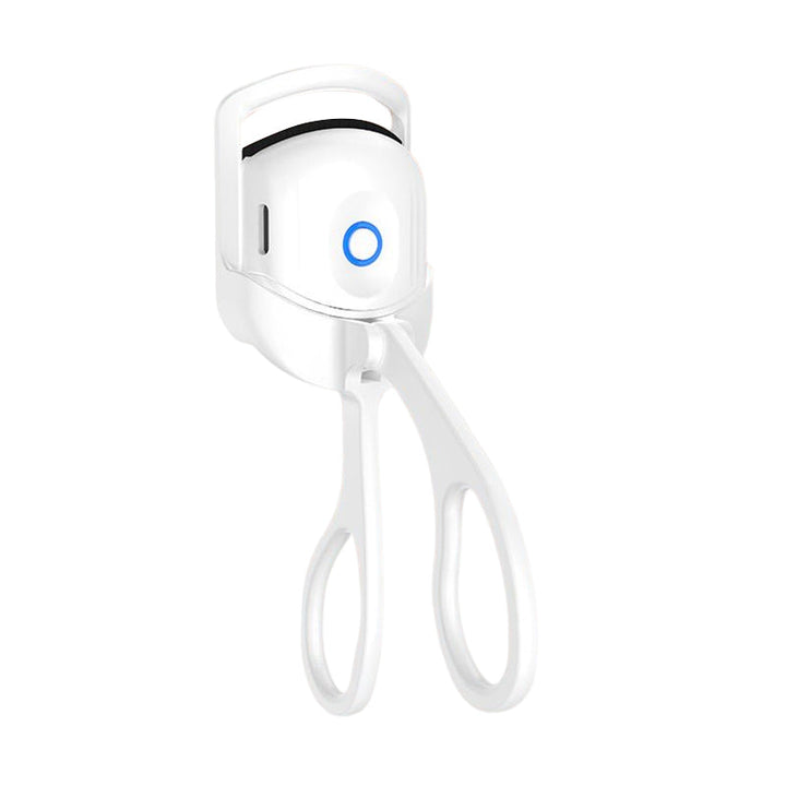 Heated eyelash curler in hand, emphasizing its lightweight and portable nature as a beauty tool