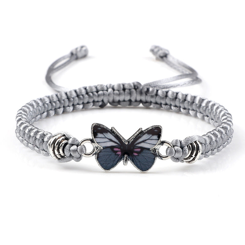 Lifestyle shot of someone wearing the black adjustable woven butterfly charm bracelet.