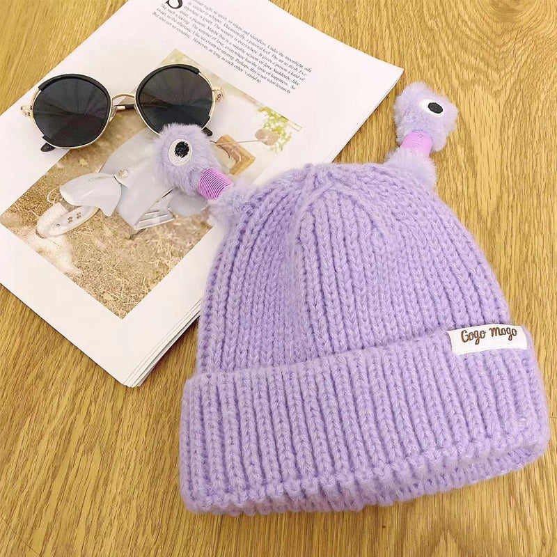 Child excitedly wearing a yellow knit monster hat, cute and cozy