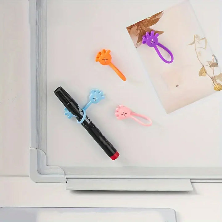 Magnetic silicone cable organizer clip in white, against a contrasting dark desktop, tidying a power cord.