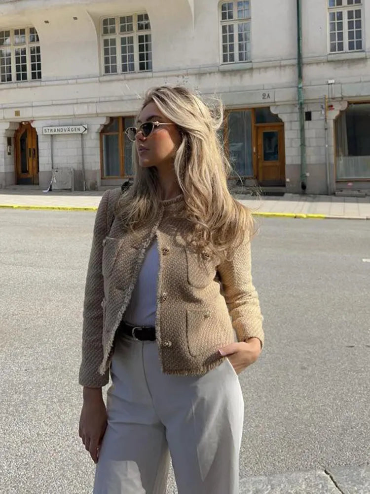 Cropped women's tweed jacket featuring a stylish design and decorative button details.