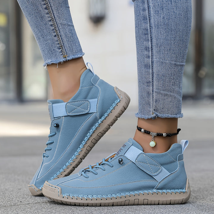 Rear view of women's comfortable flat sneakers featuring a subtle heel and unique stitch detailing on the sides.