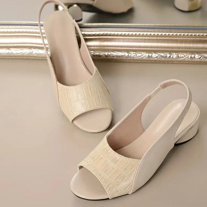 A stack of women's low block heel sandals in various colors, all with croc texture