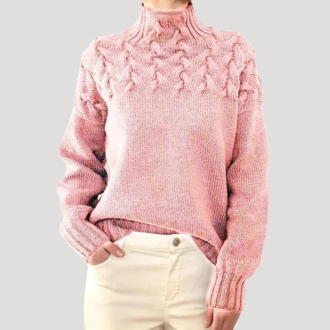 Close-up of a women's cable knit high-neck sweater showing intricate textured knit pattern