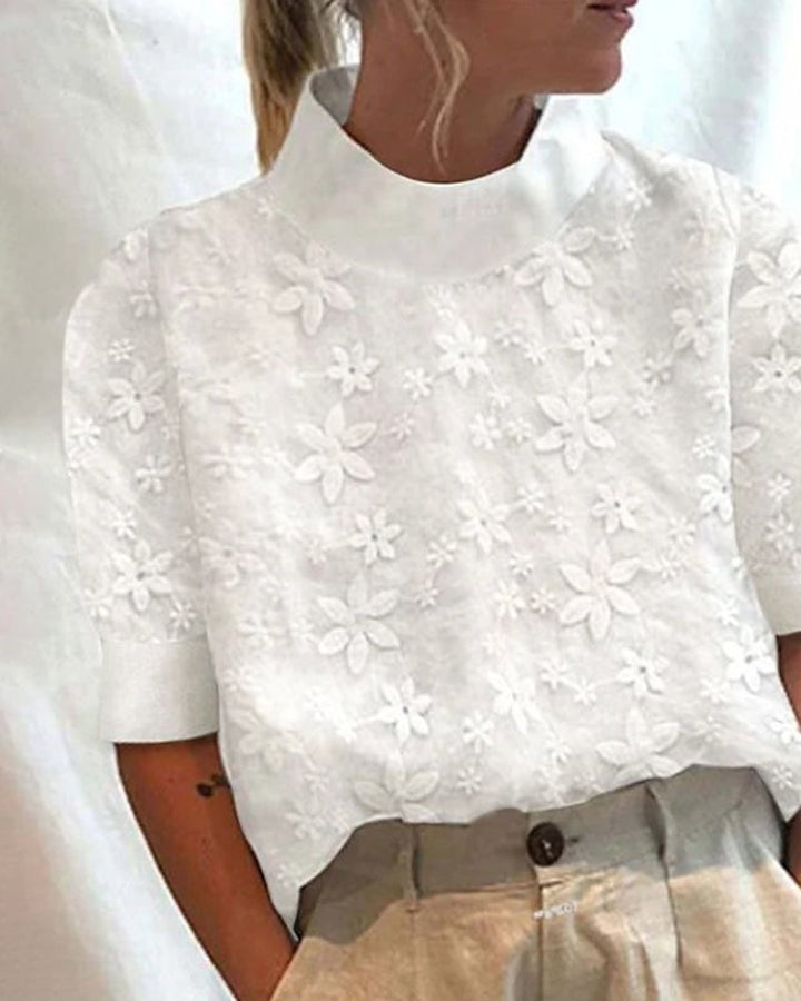 Modern women's white blouse with a stand collar & delicate floral embroidery, offering a chic and elegant fashion statement.