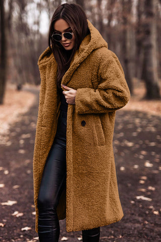Woman wearing a black faux fur hooded winter parka coat, standing outdoors in snow