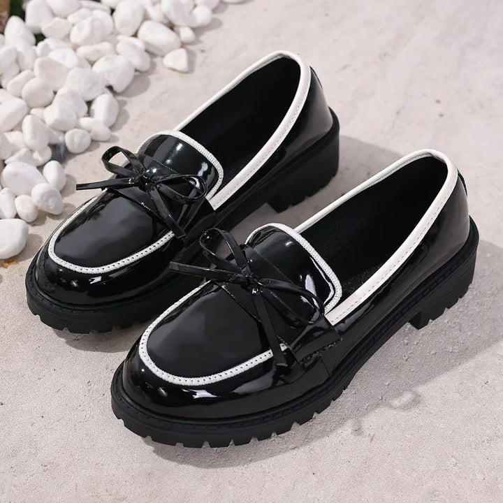 Close-up of the glossy texture on women's patent penny loafers, luxurious finish