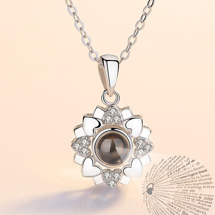 Close-up of the '100 Languages I Love You' engraving on the rose gold projection pendant.