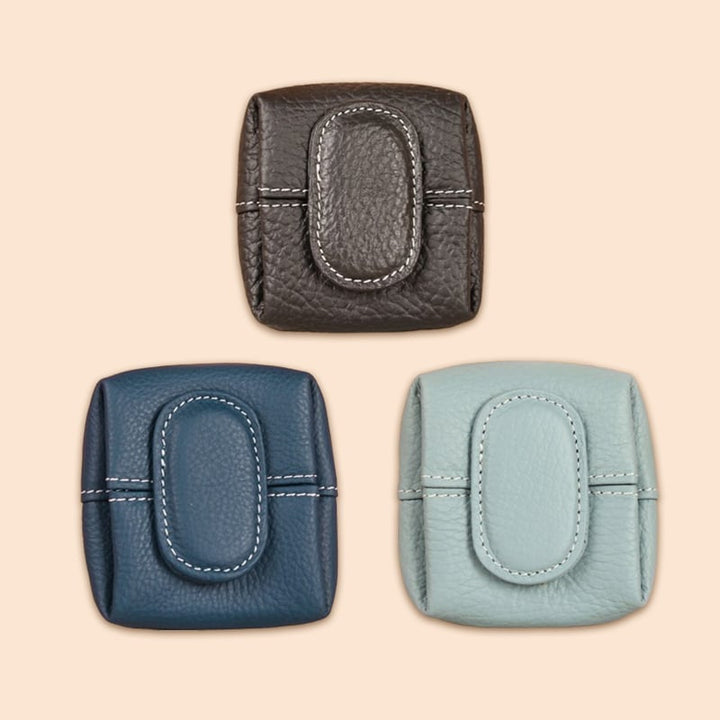Small tan leather coin purse alongside a smartphone, showing its compact size