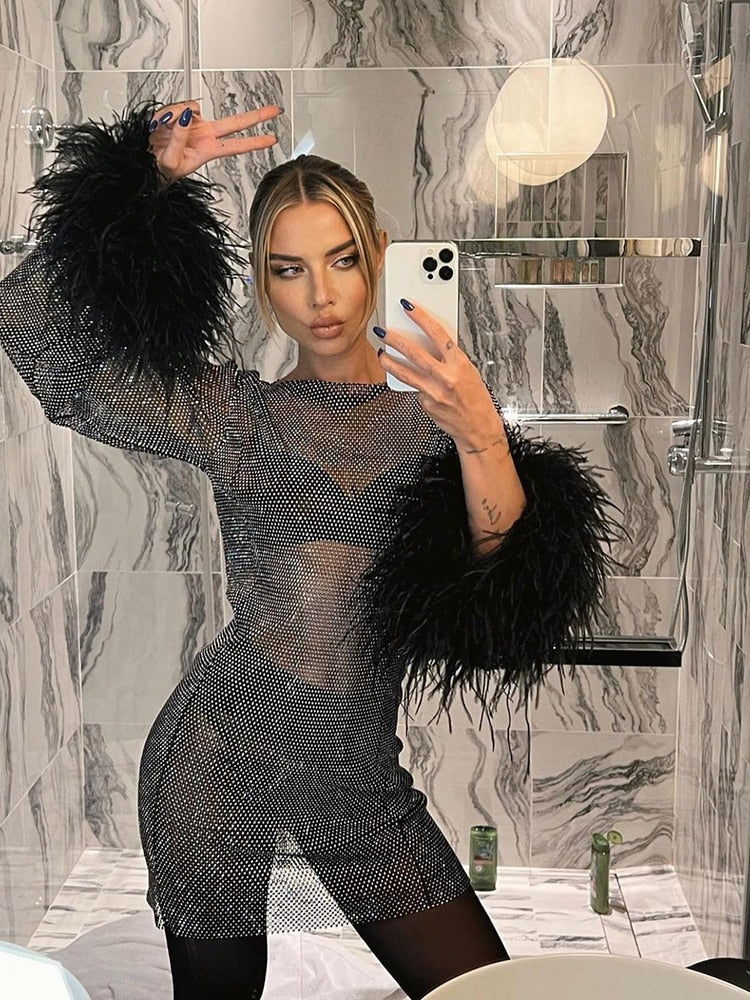 Women's glamorous sequin mini cocktail dress with sheer sleeves & chic feather trim. Special occasion.