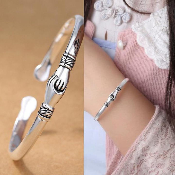 Close-up of sterling silver handshake bracelet, showing detailed clasp and handshake design