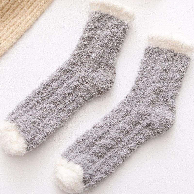 Woman wearing a pair of dark grey thermal fleece-lined winter socks, relaxing indoors.