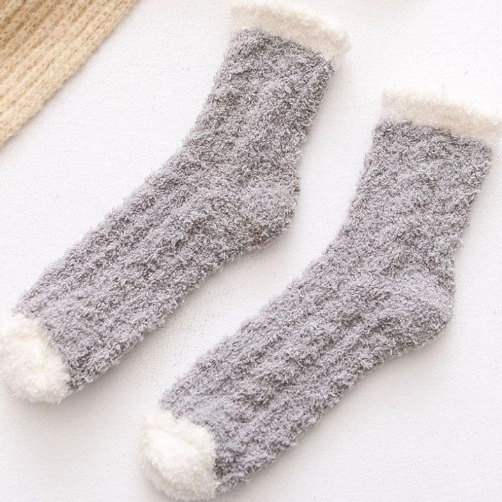 Woman wearing a pair of dark grey thermal fleece-lined winter socks, relaxing indoors.